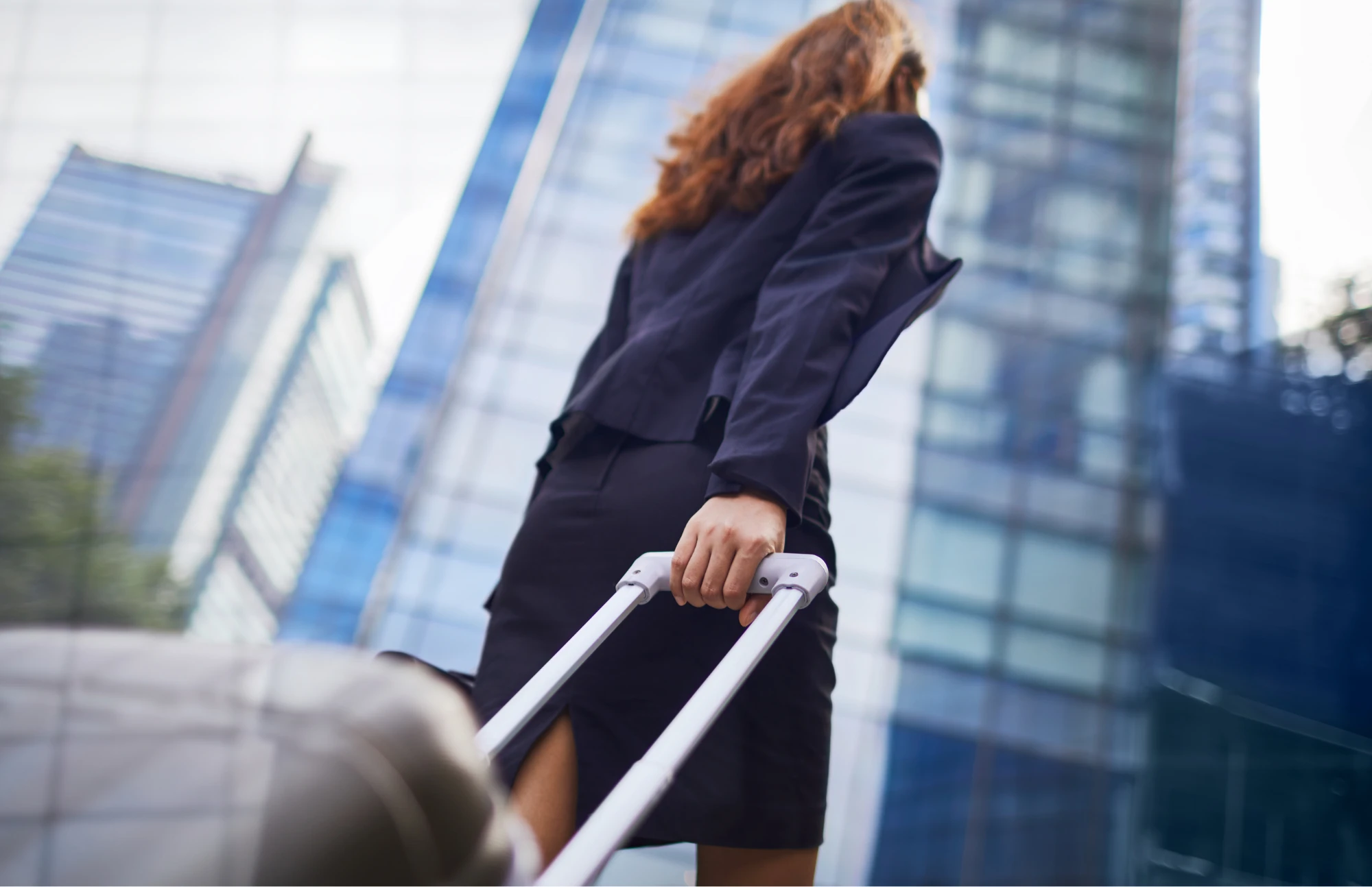 Viajera de negocios con maleta en zona corporativa